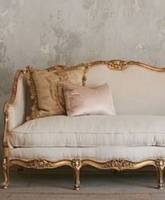 an ornate couch with pillows on it in front of a wall