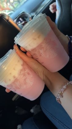 two people are holding cups with liquid in their hands while sitting in a car together