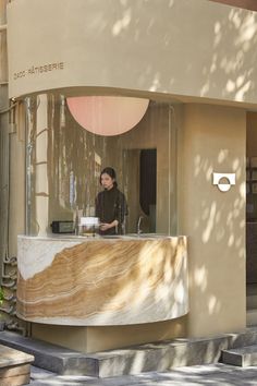 a woman standing at a counter in front of a building with a large circular window