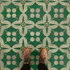 a person standing in front of a green and white tile floor with circles on it