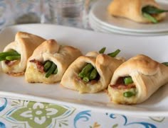 small pastries with asparagus and bacon are on a white platter next to water glasses