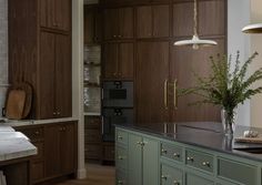 A spacious and stunning kitchen space with curved green tone island and beautiful wood cabinetry.