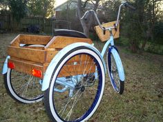 a blue and white bicycle with a wooden basket on the front wheel, parked in a yard