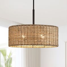 a rattan light fixture hanging from a ceiling in a living room with white walls