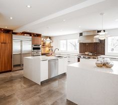 a large kitchen with an island in the middle and stainless steel appliances on both sides