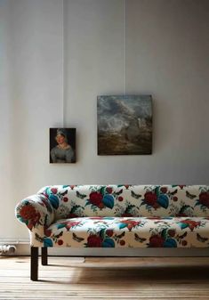 a couch sitting on top of a hard wood floor next to a painting and window