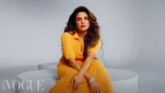 a woman in a yellow dress is sitting on a white table and posing for the camera