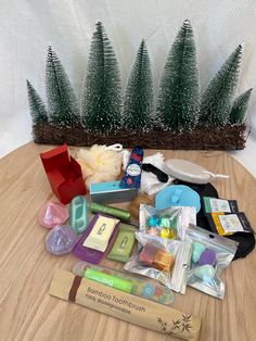 an assortment of items sitting on top of a wooden table next to small christmas trees