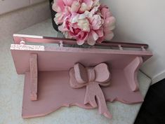 a vase with pink flowers on top of a counter next to a mirror and shelf