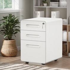 a white filing cabinet sitting on top of a wooden floor next to a potted plant