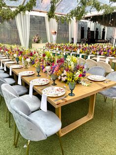 a table set up with plates and flowers in front of a large tented area