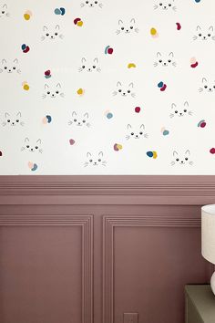 the wall is decorated with colorful cats and dots on it's walls, along with a lamp