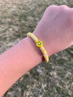 a person wearing a bracelet with a smiley face on it's wrist in the grass