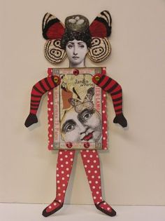 a paper doll with red and white polka dots on it's legs, holding a framed photo