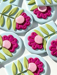 some pink and green decorated cookies sitting on top of blue plates with leaves around them