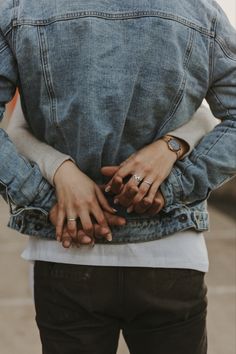 a man with his hands on his hips wearing an oversized denim jacket and matching rings