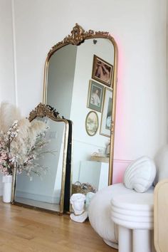 a large mirror sitting on top of a wooden floor next to a vase filled with flowers