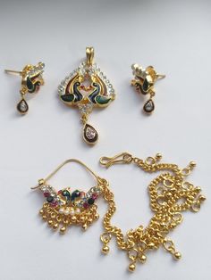 four different types of jewelry on a white surface with gold chains, earrings and pendants