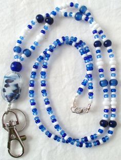 This blue & white beaded lanyard can be used as a badge holder, an I.D. holder, keychain necklace, watch holder - it's a multi-use accessory for home or office! 34" in length, long enough to put on or remove overhead. It also has an easy-to-use metal lobster clasp so you have a choice. It's made with glass beads and strung on strong (durable C-Lon beading cord. Snap-on badge holder, clip, and keyring are included to keep your badges or keys ready when you need them. This blue & white beaded lany Adjustable Beaded Blue Lanyards, Adjustable Blue Beaded Lanyards, Blue Beaded Jewelry For Everyday Use, Everyday Blue Beaded Jewelry, Blue Round Beads Jewelry For Everyday, Blue Lanyard With Key Leash As Gift, Blue Lanyard With Key Leash For Gift, Blue Lanyards With Key Leash As Gift, Handmade Blue Lanyards For Gifts