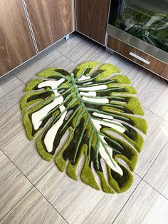 a green and white rug on the floor next to a stove with an oven in the background