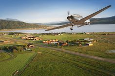 an airplane is flying low over a small town and lake in the middle of nowhere