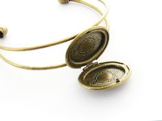 "Photo Locket Bracelet, Picture Locket Bangle, Victorian Jewelry, Keepsake Jewelry, Antiqued Gold - Can hold 2 photos, a lock of hair, a little message and so much more. Materials - antiqued gold finished brass The locket is soldered onto the 2 bangle wires. Oval Locket: Photo area: max 0.88 x 0.62 inches on one side, and the flat area on the other side is 0.68 x 0.5 inches To print a photo to fit on the flat part on the left, open the image, and if its in portrait orientation (i.e., the long ed Adjustable Antique Gold Cuff Bracelet Gift, Adjustable Antique Gold Cuff Bracelet As Gift, Bracelet Picture, Lock Of Hair, Picture Locket, Locket Bracelet, Round Locket, Oval Locket, Hair Locks