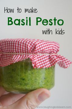 a hand holding a jar with pesto in it and text overlay reading how to make basil pest with kids