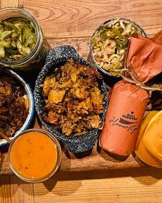 a wooden tray topped with different types of food next to sauces and condiments