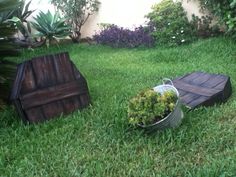 an empty bucket sitting in the grass next to a wooden bench and potted plant