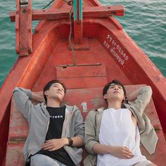 two people laying down on the back of a boat in the water with their eyes closed