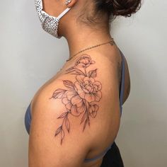 a woman with a flower tattoo on her back shoulder and behind her head is a leopard print mask