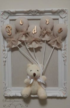 a teddy bear hanging from the side of a frame with flowers and letters on it