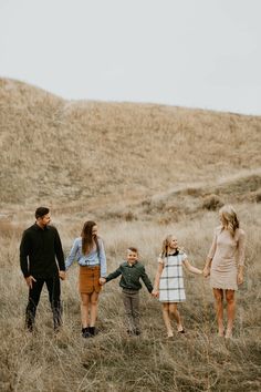 a family holding hands and walking through tall grass