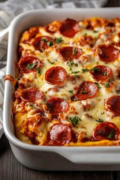 a square casserole dish with pepperoni and cheese on top, sitting on a wooden table