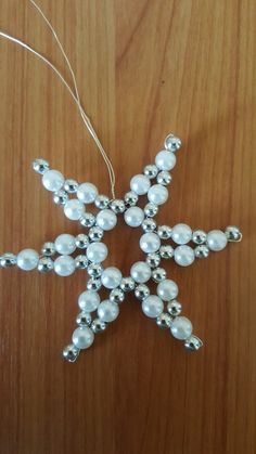 a snowflake ornament made out of beads on a wooden table top