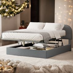 a bed sitting on top of a white floor next to a christmas tree