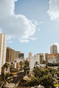 the city is full of tall buildings and palm trees in front of blue sky with white clouds