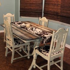 a dining room table and chairs with cow hide rugs on the chair back cushions