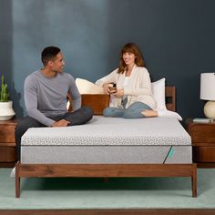 a man and woman sitting on top of a bed