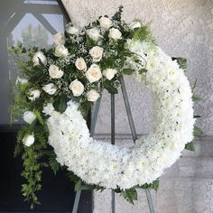 a wreath with white flowers and greenery in front of a building