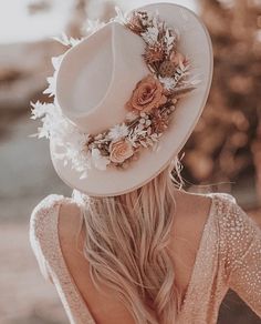 a woman wearing a white cowboy hat with flowers on the brim and back of her head