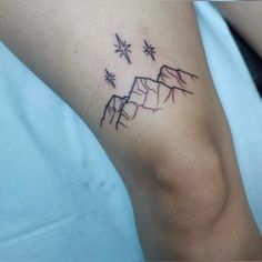 a tattoo on the leg of a person with mountains and stars in the sky above them