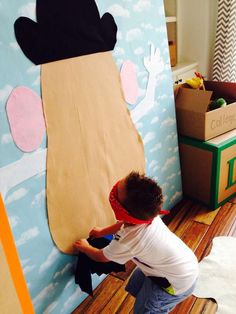 a young boy is playing with a large cardboard bear on the floor in front of a wall