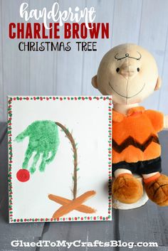 a handprinted christmas tree is next to a stuffed animal