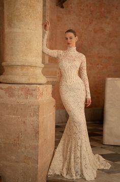 a woman in a wedding dress leaning against a pillar