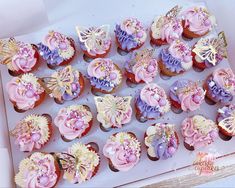 there are many cupcakes in the box with butterflies on them and pink frosting