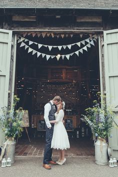 a bride and groom standing in front of an open barn door at their wedding reception