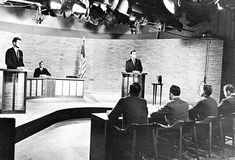 three men are sitting at podiums in front of an audience