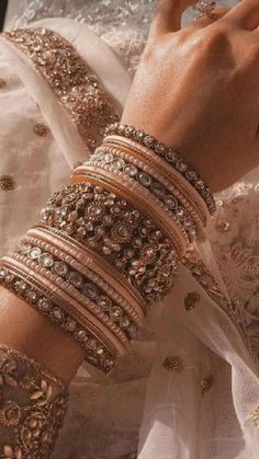 a close up of a person's hands wearing bracelets and rings on their fingers