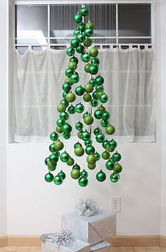 a christmas tree made out of green balls hanging from it's sides with presents underneath